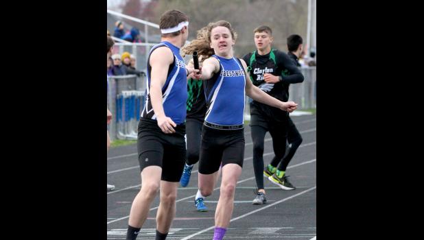 Topher Bigalk, right, hands the baton to Ethan Mast during the distance medley relay.
